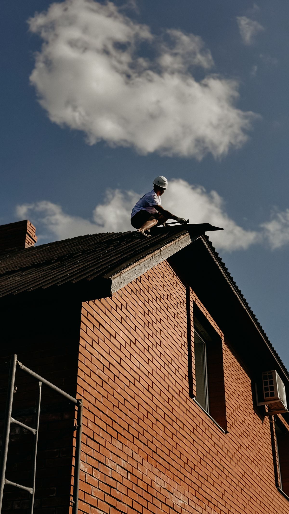 A UK tradesperson at work on a brick house roof
